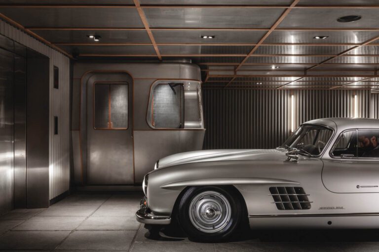 A Mercedes 300SL Gullwing parks in front of the security room; the floors are stone tile, while the walls are clad in custom GRC panels and the ceiling in untreated stainless steel.