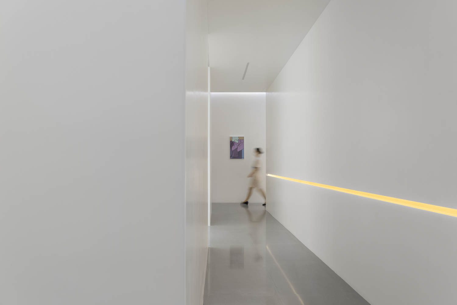 Yellow linear lights, and contemporary art, seem to glow against the resin paint of the passageway walls.