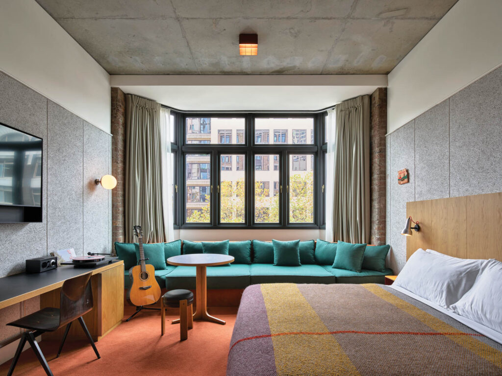 Applied to a guest room’s walls, acoustic ceiling panels form a kind of tall dado that, despite in-room guitars and stereo equipment, is more about aesthetics than soundproofing.