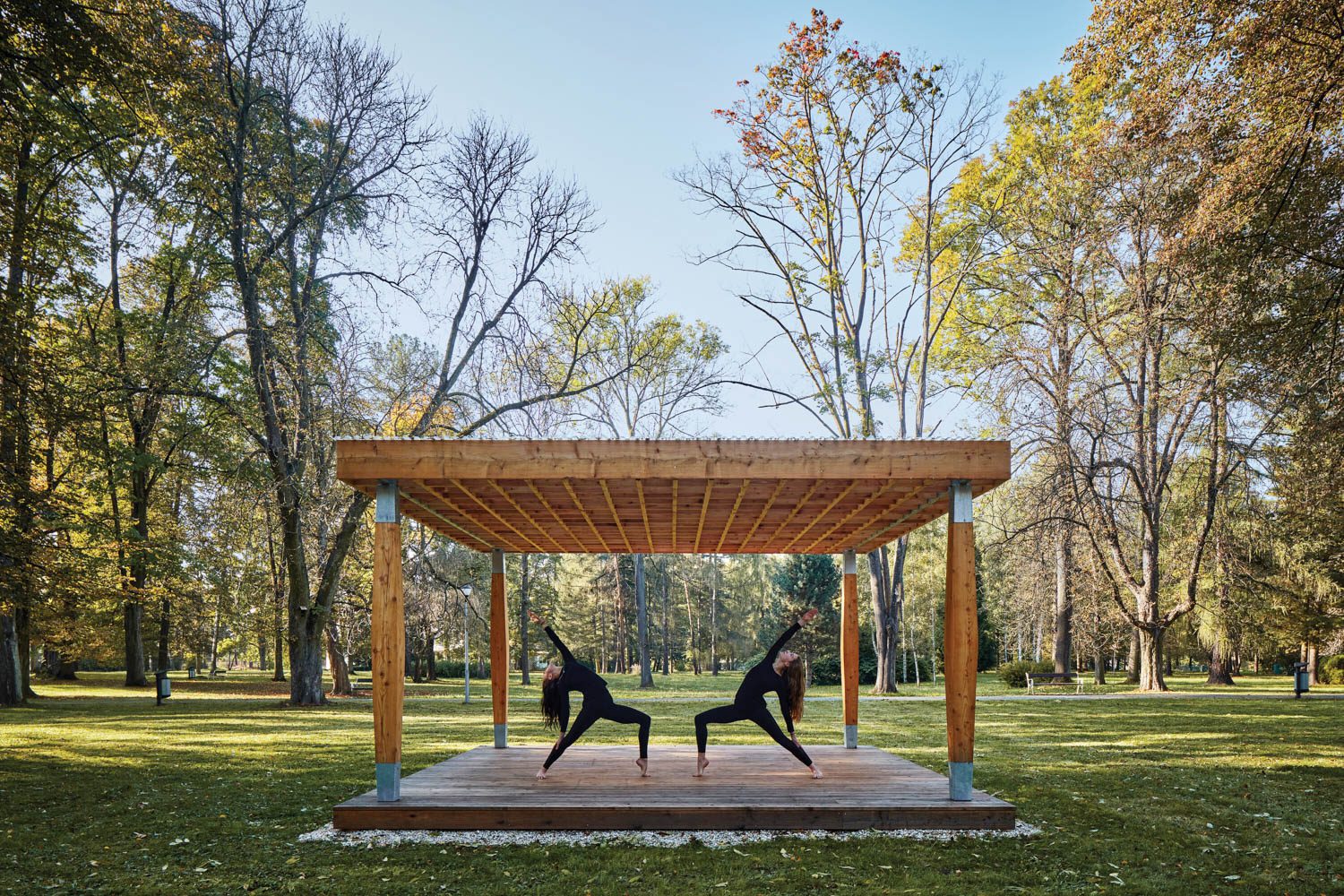 two women do yoga on a pavilion