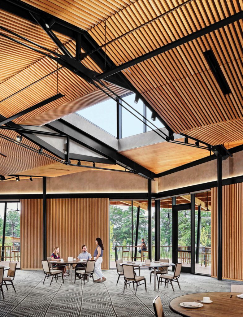 The multifunction dining-seminar space has a ceiling and walls of hemlock slats, interspersed with broad swaths of glass.