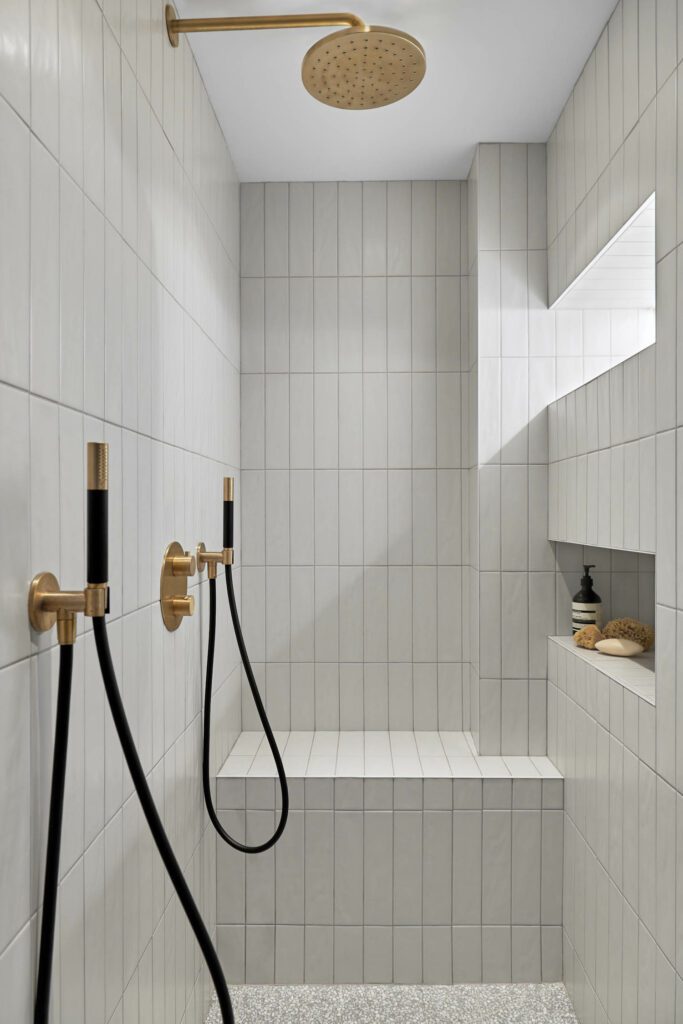 a tiled shower with gold fixtures