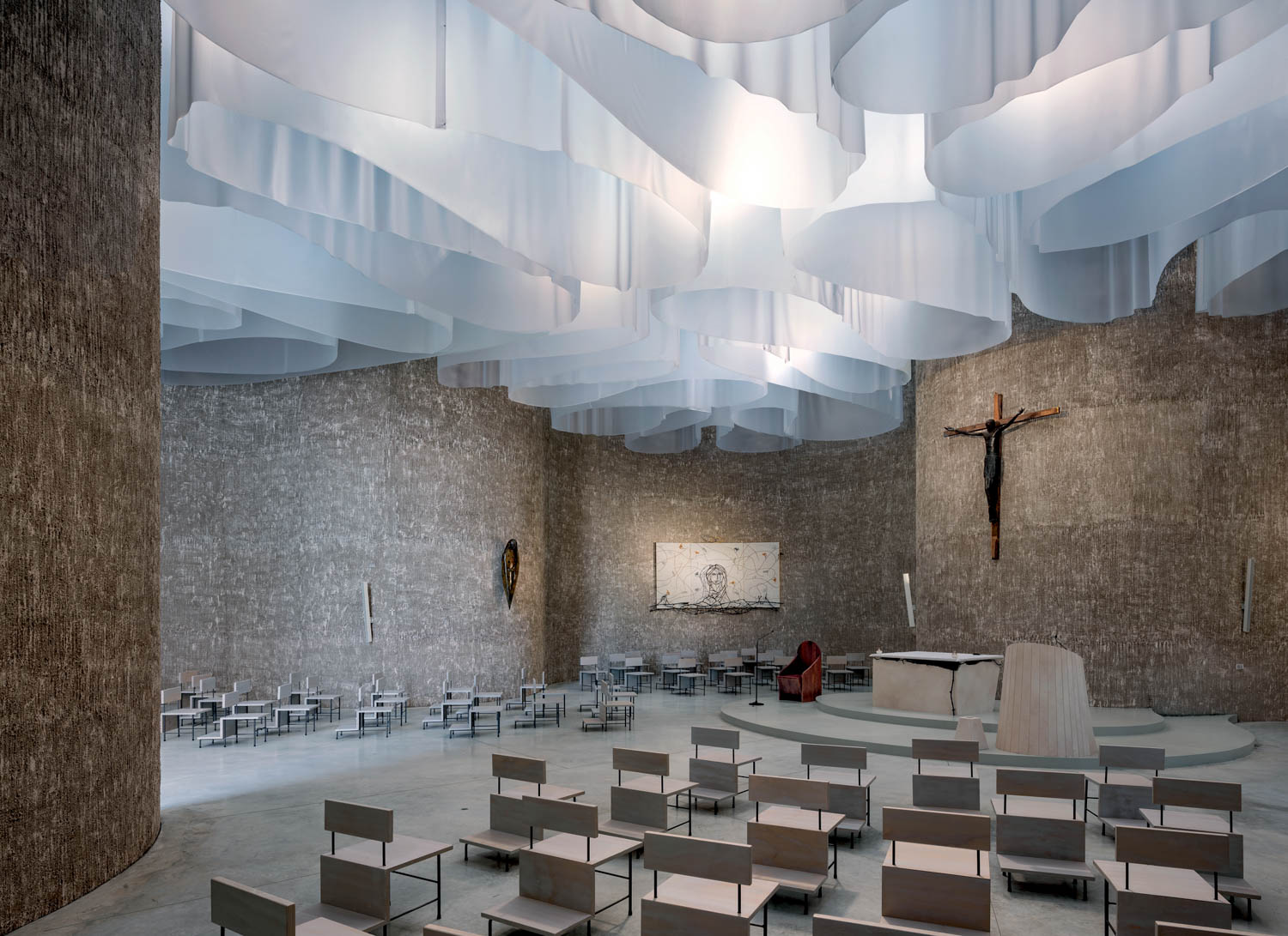 The church interior featuring walls of hemp-and-lime render and light-diffusing drapes.