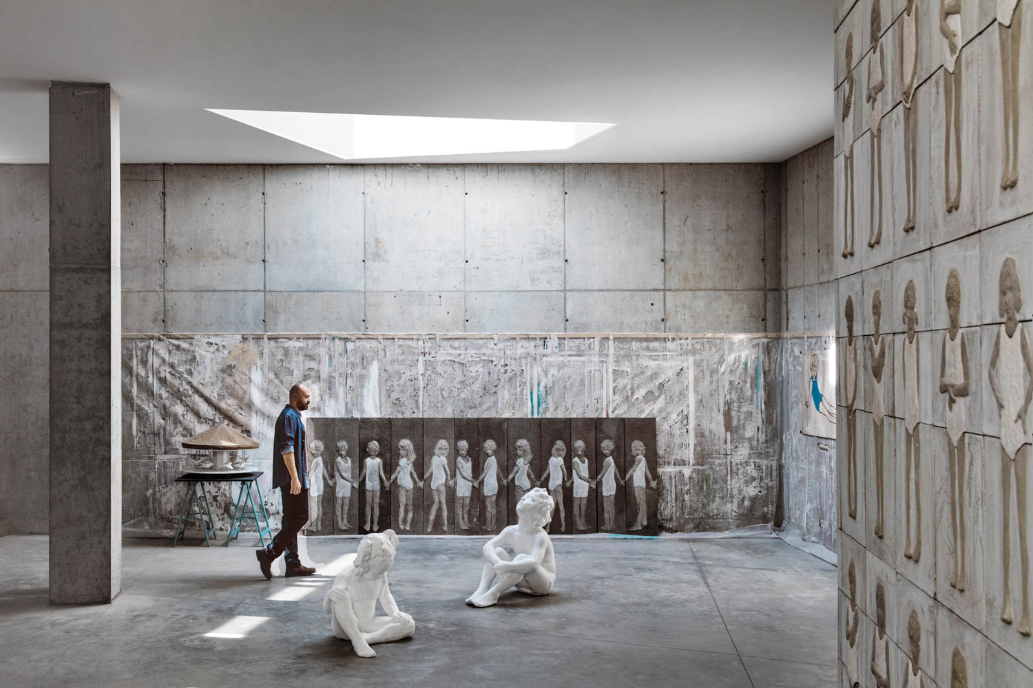 Paneling and flooring of cast on-site concrete surround the atelier portion of the home and studio of artist Valerio Berruti, who’s over­looking his polystyrene sculptures representing his two children, Nina and Zeno, a ground-up project in Alba, Italy, by SBGA | Blengini Ghirardelli.