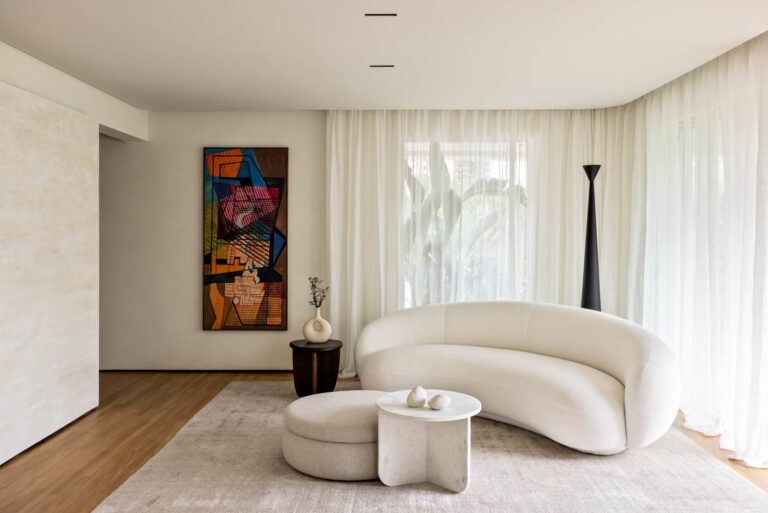 In the living room, a sofa by Jonas Wagell mixes with a marble coffee table by Estudio Rain and a hardwood side table by Estúdio Orth, while the artwork is by Roberto Burle Marx.