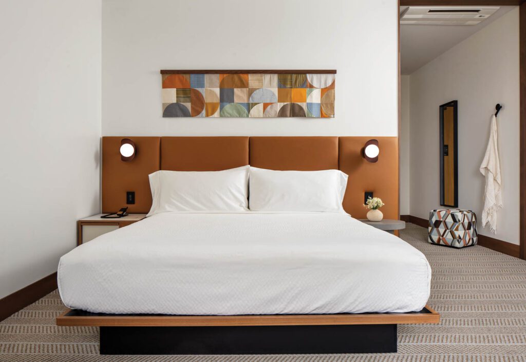 Anni Albers–inspired art by Cory Siegler hangs above the custom platform bed and vinyl-upholstered headboard in a guest room.