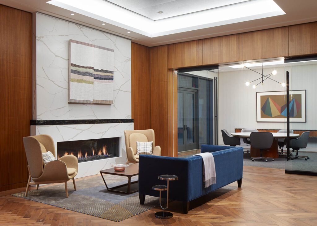 On the seventh floor, an executive lounge boasts a Mitchell Gold Bob Williams sofa, Fogia armchairs, Bernhardt coffee table, and custom quartz hearth with Cambria ledge; the meeting room in the rear offers a Halcon table and Geiger chairs, with artwork by Sol LeWitt.