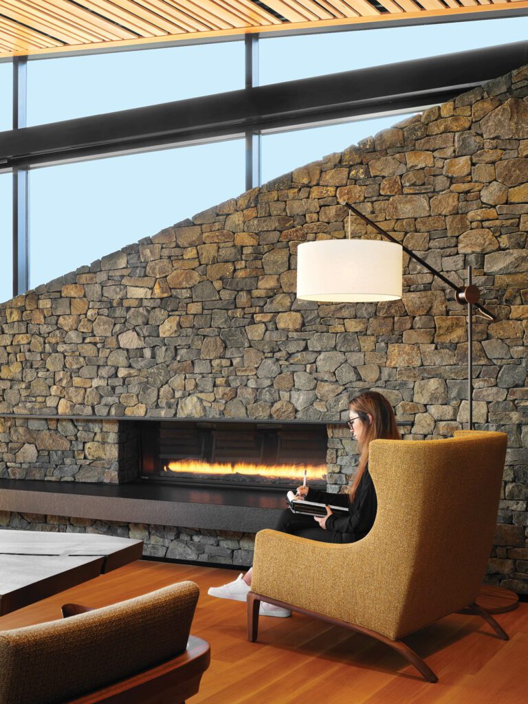a stone wall overlooks a sitting area with a wing chair