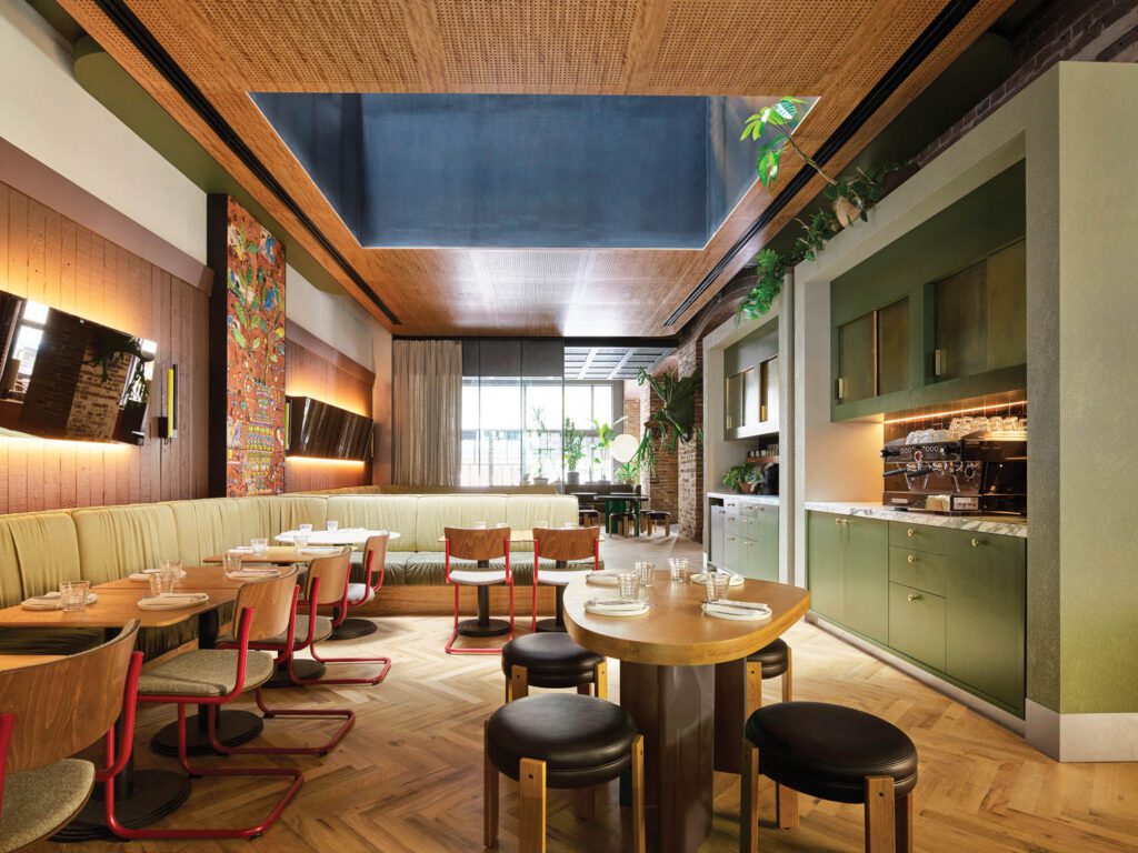 In the lobby restaurant, perforated panels of blackbutt, a kind of eucalyptus, clad the ceiling, herringbone-pattern oak boards cover the floor, and Mart Stam tubular-steel chairs mix with custom booth seating and tables.