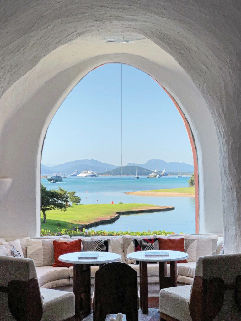 An arched lobby window frames a view of the Med­iter­ranean Sea’s Costa Smeralda.