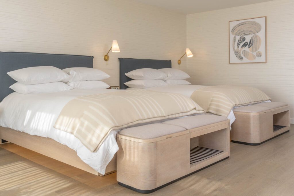 Two beds in a guest suite with custom headboards and oak flooring. 