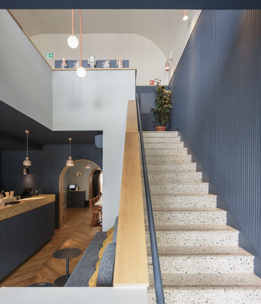 The first floor stairs are terrazzo, with walls of half-moon slatted wood and brass finish detailing.