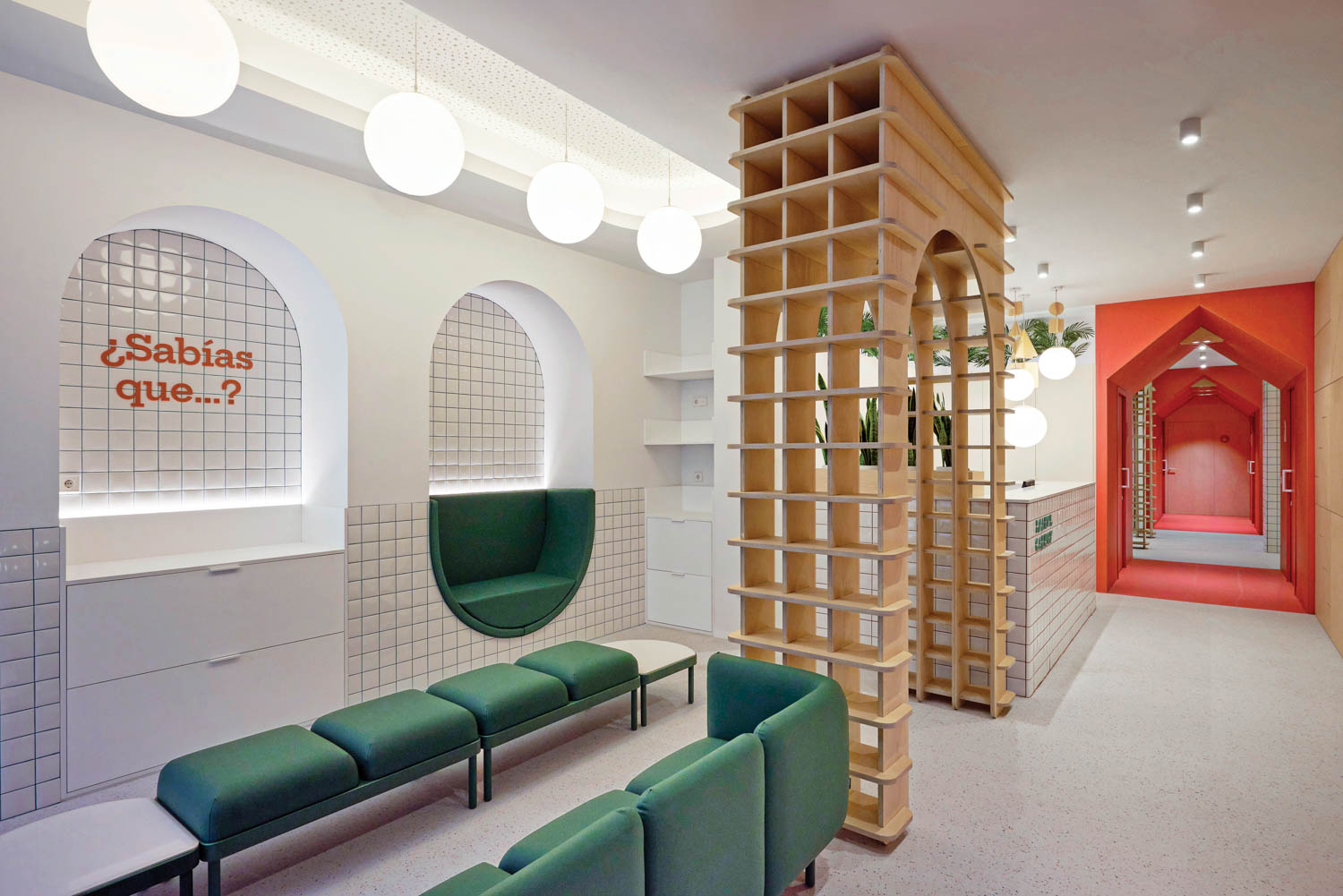 Interlocking plywood pieces form a custom arch in reception, part of the project’s learning-based theme (child-centered reading materials are stored beneath the ¿Sabías que…? mural, which translates to Did you know?).